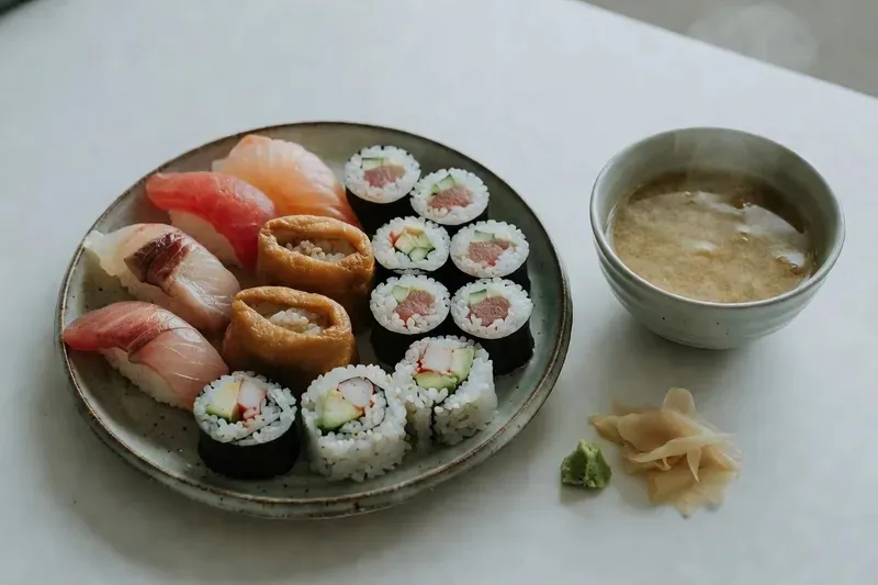 Small group of four carefully placing toppings on nigiri sushi at a three-hour sushi making class in Shinjuku Tokyo